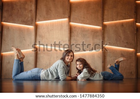 Portrait of a happy smiling mother with red lips and little cute daughter on an isolated dark background. Mom and daughter hugging.
