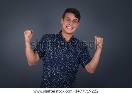 Caucasian blond man rejoicing his success and victory clenching his fists with joy. Lucky man being happy to achieve her aim and goals. Positive emotions, feelings.