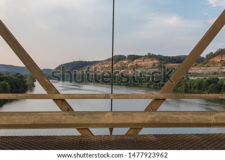 V shaped beams frame a view of a mountainside and river with cloudy skies
