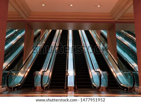 Perfect and balanced escalators with mirrors on the sides and light soft reflections on the floor, ceiling, and metal.