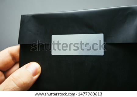 Man hand holding black plastic secret letter with VOID sticker on the cover