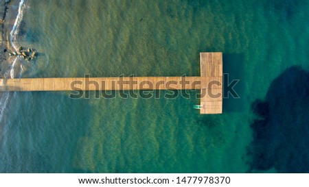 Top view of wooden pier with ocean water, marina aerial view. Aerial drone view of touristic wooden pier in the middle of the blue sea with parasols and sunbeds on a summer day. Holiday Summer