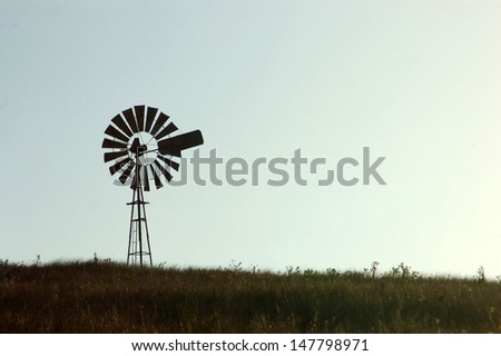 Silhouette of windmill in paddock, Queensland, Australia. Windmills are commonly used for pumping water from bores or dams to troughs for livestock.