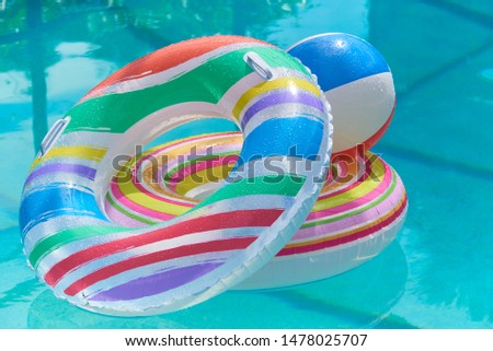 Summer. Pool floats and a beach ball piled on each other floating in a swimming pool 
