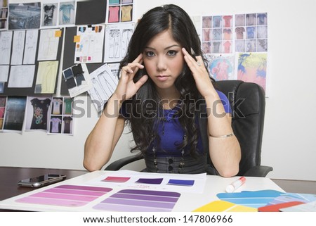 Portrait of a tensed female fashion designer working at desk