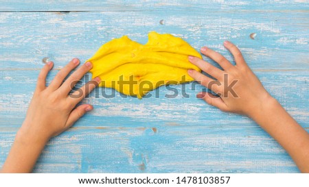 Child slime yellow smears on the wooden table. Toy antistress. Toy for the development of hand motor skills.