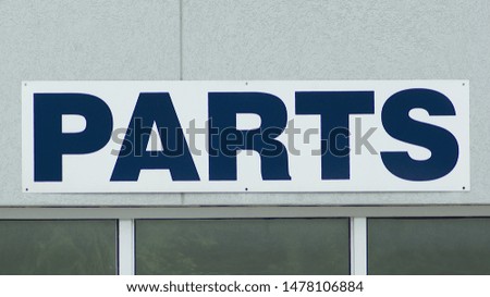 Steel "PARTS" sign screwed to wall.