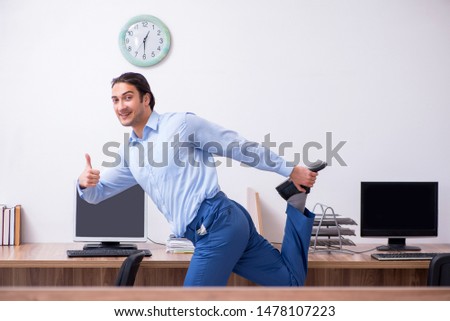 Young handsome businessman doing exercises at workplace 