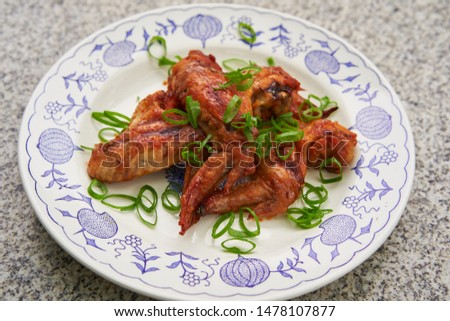 Close up Picture on the spicy barbecue chicken buffalo wings marinated in soya sauce, ketchup, chili and honey served on the vintage rustic plate on stone table with green chopped fresh spring onion.