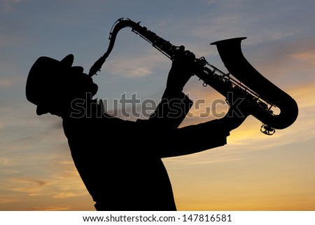 Saxophonist. Man playing on saxophone against the background of sunset Royalty-Free Stock Photo #147816581