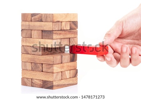Woman hand holding red block from stacked wooden block on white background. Symbol of leadership, teamwork and different. Business and design concept.