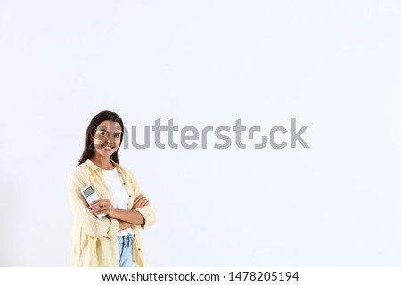 Young woman with air conditioner remote on white background