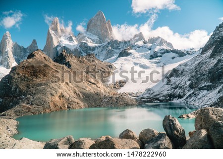 Scenic view of snowcapped mountain tops of Mount Fitzroy, Patagonia trek. Blue sky background with turquoise blue lake and scenic rock landscape. Shot in Argentina. Nature, travel, adventure, hiking.
