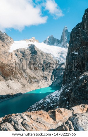 Scenic view of snowcapped mountain tops of Mount Fitzroy, Patagonia trek. Blue sky background with turquoise blue lake and scenic rock landscape. Shot in Argentina. Nature, travel, adventure, hiking.