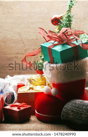 Green gift box in Santa Claus shoes decorate with group of gift boxes on the wood table for Christmas theme.