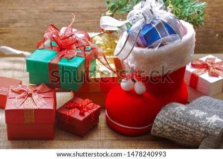 Blue gift box in Santa Claus shoes decorate with group of gift boxes on the wood table for Christmas theme.