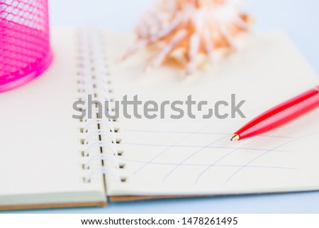 Red pen and seashell on notebook. Red pen on pastel background. Surreal business concept. Copy space