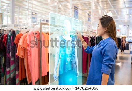 futuristic technology concept.happy girl try to use smart hologram display with virtual augmented reality in the shop or retail to choose select ,buy clothes and change a color of products. Royalty-Free Stock Photo #1478264060