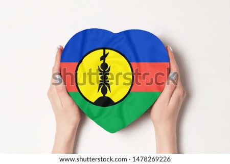 Flag of New Caledonia on a heart shaped box in a female hands. White background