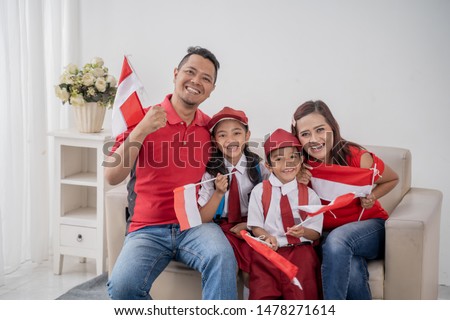 proud indonesian family holding indonesia flag over white background on independence day