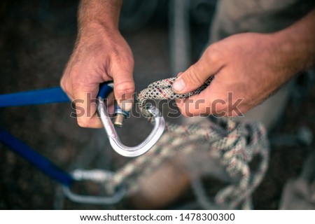Top view picture of industrial rope access worker hand connecting locking screwgate Karabiner 2.5 tone Nylon low stretch rope which its attached onto safety tape sling and beam structure anchor point