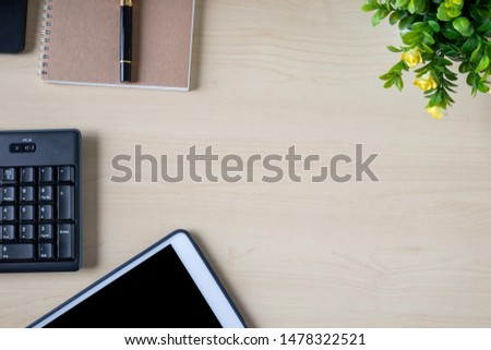 Top view of work desk with tablet, notebook, pen, keyboard and ornamental tree