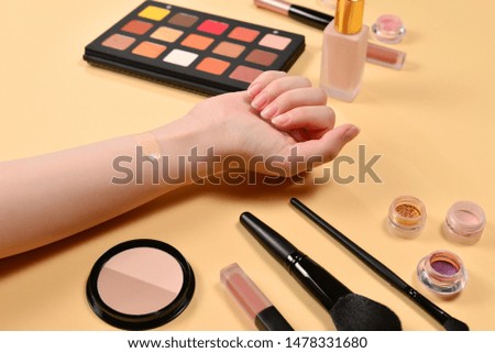 Foundation on woman hand. Professional makeup products with cosmetic beauty products, foundation, lipstick,  eye shadows, brushes and tools.