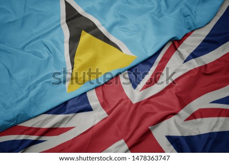 waving colorful flag of great britain and national flag of saint lucia. macro