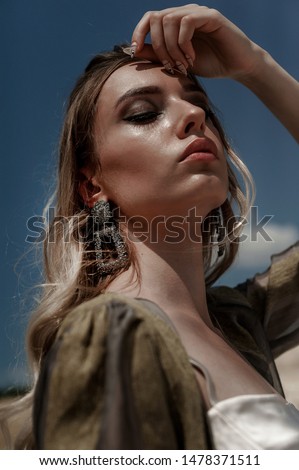 blonde girl posing in clothes against the sky and cracked white clay
