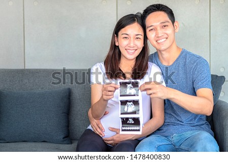 Ultrasound pregnant mom and dad. Happy pregnant woman with husband show the scan of their baby. Happy couple are holding the baby ultrasound photo.