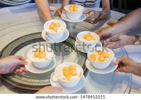 Atmosphere Chinese cuisine dish on the table. Chinese restaurant. Asian family is taking a dessert bowl with spinning sago cantaloupe fruit. Cheers concept. Happy meal