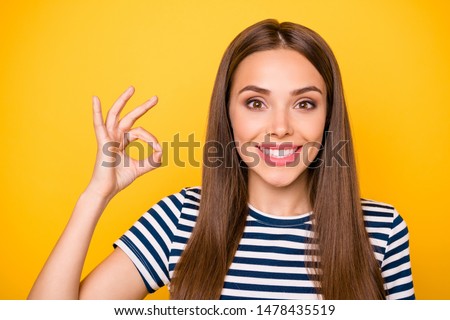 Close up photo of lovely lady showing okay signs advertising promotions wearing striped t-shirt isolated over yellow background