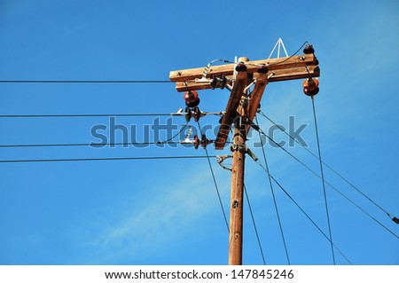 Electric pole in front of a clouded blue sky