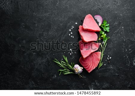 Raw tuna fillet. Seafood on a black stone background. Top view. Free copy space. Royalty-Free Stock Photo #1478455892