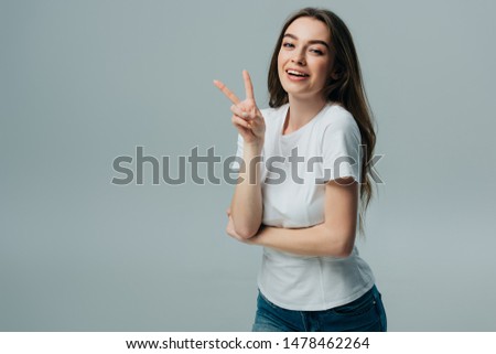 beautiful happy girl showing peace sign isolated on grey