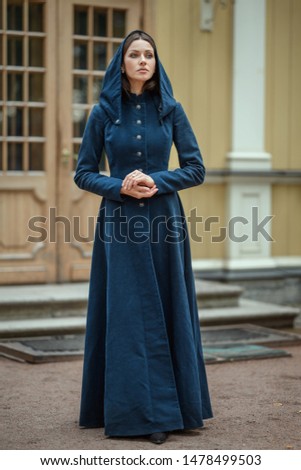 Portrait poetic brown hair brunette sister beautiful woman girl  vintage classic coat dress look camera green eyes hands together street old town scenic wooden door with glass steps wall yellow white Royalty-Free Stock Photo #1478499503