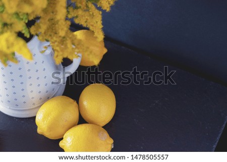 Lemons on a dark background with a white jug