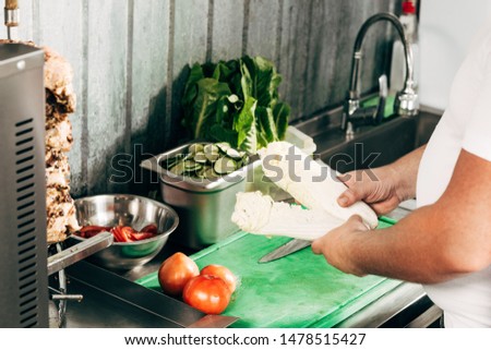 partial view of cook holding lettuce at workplace
