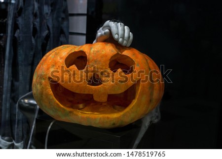 Halloween carved pumpkin Jack o' lantern and mannequin hand with spider in dark room