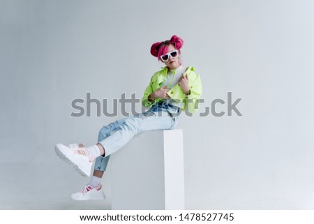 woman with pink hair in glasses sits on a cube