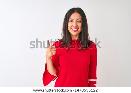 Young beautiful chinese woman wearing red dress standing over isolated white background doing happy thumbs up gesture with hand. Approving expression looking at the camera showing success.