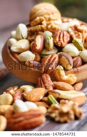 Mix nuts in wooden plate on wooden table background.Nuts including Cashew,hazelnuts,walnut,almonds, Brazil nuts,pecan and macadamia.Intake a handful of nut a day can stave off various disease.Vertical Royalty-Free Stock Photo #1478544731