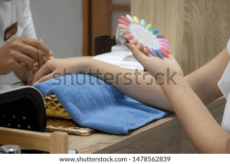 Girl with beautiful manicure finger selects new varnish from color palette,woman chooses the color of polish for manicure