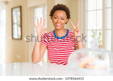 Young beautiful african american woman at home showing and pointing up with fingers number seven while smiling confident and happy.