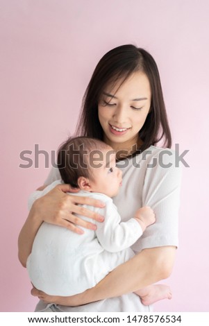 Mother holding her baby against pink background