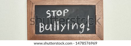 panoramic shot of chalkboard in wooden frame with stop bullying lettering on grey background