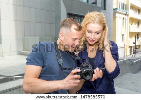 Male photographer shows a woman photographs in a camera after a photo shoot. Couple is traveling.