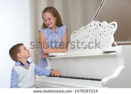 Two little kids girl and boy playing piano in living room or mus