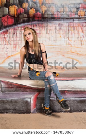 Young Caucasian female with skateboard looking over