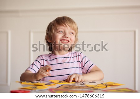 happy cute boy 5-6 years old sits at a table and paints pictures with road signs, the child develops in the process of education
